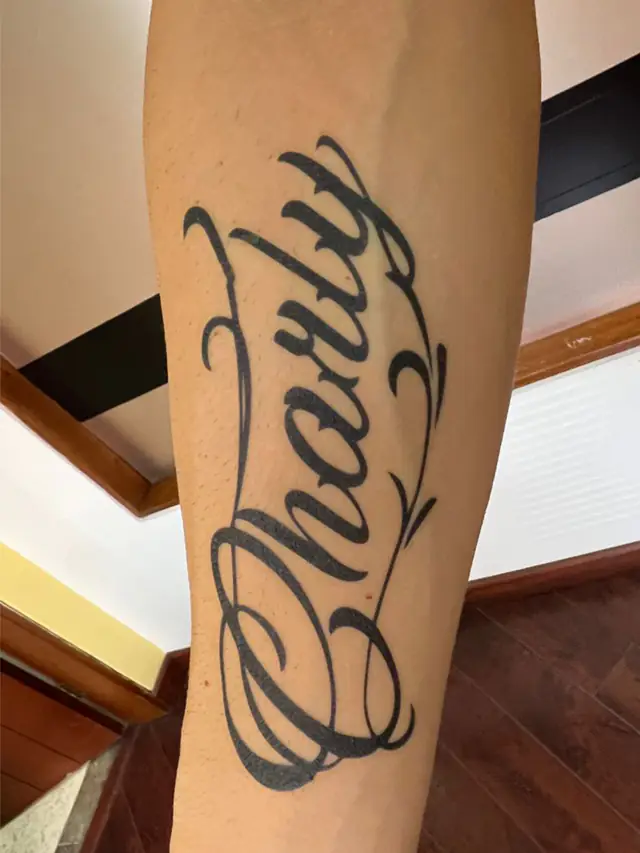 Tatuaje temporal caligráfico con el nombre Charly aplicado en el antebrazo para Caracol